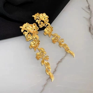 Detailed macro of golden matte metal flower earrings with long leaf drop design