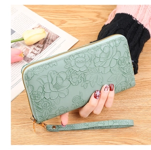 Detail of green floral embossed long wallet with golden zipper and detachable wrist strap