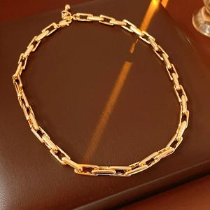 Detail view of a gold-toned chunky chain link necklace laid on a warm brown surface