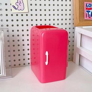 Detailed view of a pink mini fridge-shaped desk organizer with a white handle on a white board