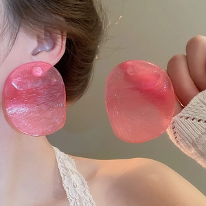Close-up of pink translucent oversized resin hoop earrings with brushed texture