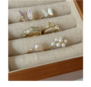 Macro detail of gold-plated butterfly rings and pearl jewelry in a wooden organizer box