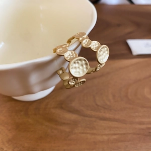 Detailed view of gold irregular geometric C-shaped earrings on a beige ceramic cup