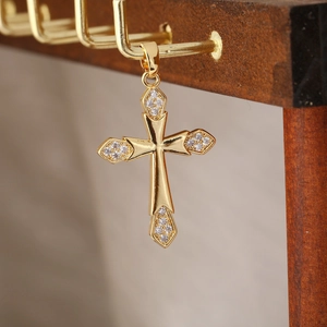 Dettaglio della collana con ciondolo a croce dorata con zirconi su espositore in legno