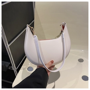 Detail view of white half-moon shoulder bag with golden zipper and red inner lining