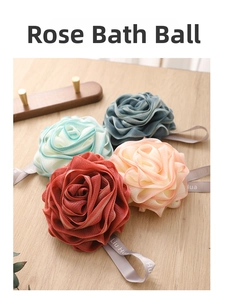 Close-up of four colorful rose shaped bath sponges with hanging ropes on wood table