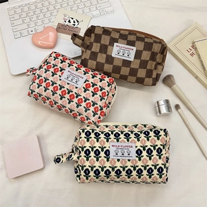 Three corduroy cosmetic bags with floral and checkered patterns on a stylish desktop