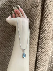 Macro view of silver snake chain with a translucent pale blue teardrop pendant