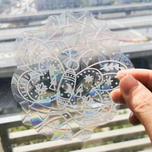 Detailed holographic suncatcher sticker with moth and moon design held against window light