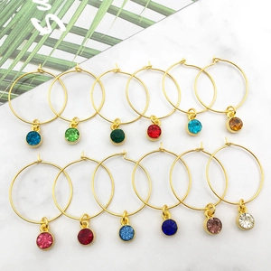 Set mit 12 farbigen Kristall-Ohrringen mit Goldfinish auf weißem Marmorhintergrund