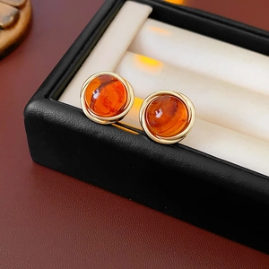 Macro detail of amber resin earrings with spiral gold trim on black leather box