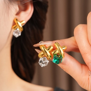 Detailed close-up of vintage gold earrings with green and clear cubic gemstones