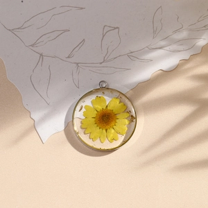Handmade botanical resin pendant with yellow dried flowers and gold leaf in silver ring