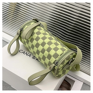 Close-up of green checkerboard cylinder bag with pleated texture and wide fabric strap