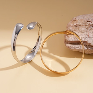 Detail of irregular silver open bangle and gold circular bracelet on a natural stone base