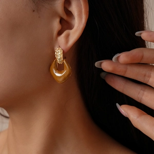 Detail of retro amber resin geometric earrings with hammered gold texture worn by a model