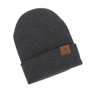 Detailed macro view of dark grey knitted beanie featuring a brown M logo leather label