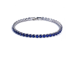 Macro detail of silver tennis bracelet featuring round deep blue zircon in a claw setting