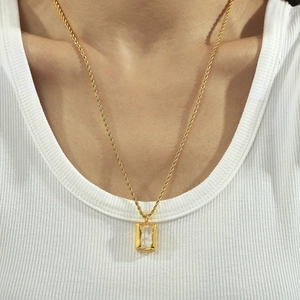 Gold twist chain necklace with a zircon square pendant worn on a white sweater background
