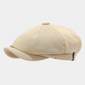 Detail of beige newsboy hat showing mesh knit texture and decorative leather patch