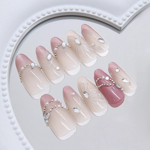 Pink cat eye press-on nails with butterfly pattern pearls and rhinestones on heart tray