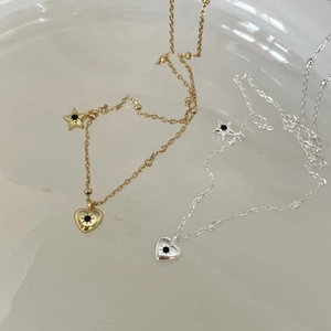 Detail of gold and silver heart and star pendant necklaces with beaded chain on grey surface