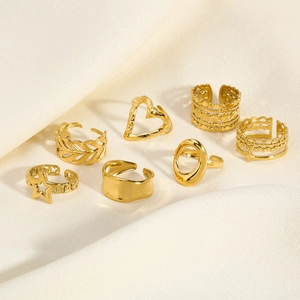 Detailed set of seven golden stainless steel rings with heart and star patterns on silk
