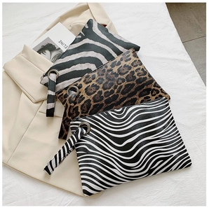 Three stylish animal print clutch bags with leopard and zebra patterns on a beige blazer