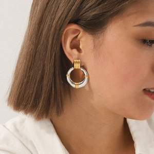 Polished two-tone gold and silver hoop earrings on female model in a modern style