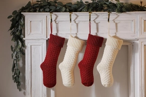 Detail of red and cream cable knit Christmas stockings hanging on a white mantel