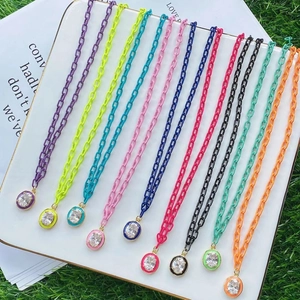 Macro shot of colorful oval pendants set with crystal on silver chains over white display