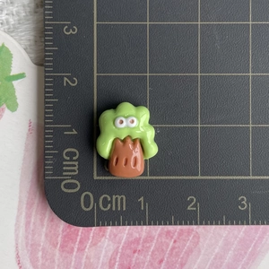 Macro shot of a tiny green resin tree accessory on a measuring scale for precise size