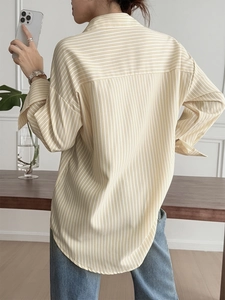 Detail view of yellow striped long sleeve vest shirt with back pleats and curved hem