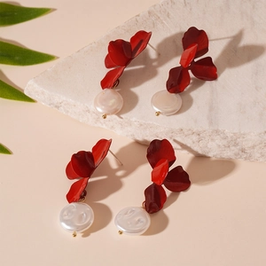 Elegant red flower earrings with freshwater pearls on a white textured stone surface