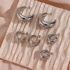 Three sizes of silver geometric hollow hoop earrings on marble with pink satin backdrop
