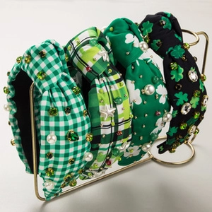 Detail of four green knotted headbands with shamrocks, pearls and rhinestones on a gold rack
