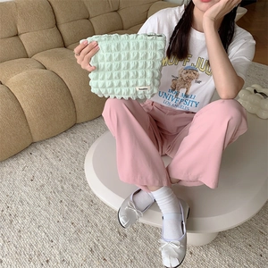 Detail of light green bubble texture vanity bag held by hands in a cozy home setting