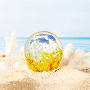Detailed macro view of crystal ocean globe with dolphins and coral on a sandy beach