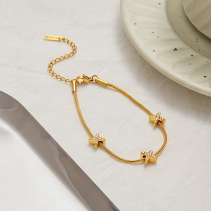 Dettaglio del bracciale a catena serpente in acciaio dorato con tre ciondoli a stella
