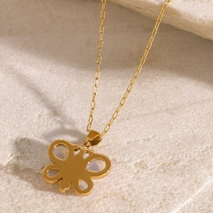Detail of a golden butterfly pendant necklace on a natural white stone background