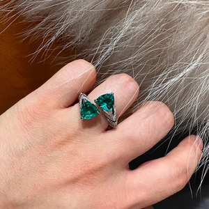 Detail of silver snake-scale ring with two green triangle zircons on model finger