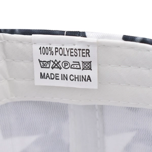 Detail of white textile care label showing 100% polyester and washing icons on cap