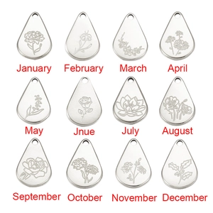 Twelve stainless steel teardrop flower pendants with monthly engravings on white background
