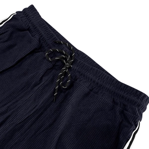 Detail of navy corduroy joggers showing black drawstrings and side stripe texture