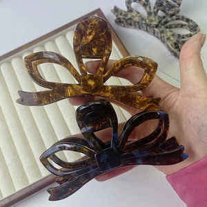 Dettaglio della clip per capelli a fiocco in acetato tartarugato ambra e blu scuro