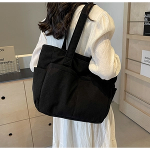 Détail du sac cabas en velours côtelé noir montrant la texture et les poches avant