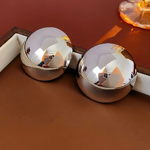 Macro shot of large silver hemispherical stud earrings on a dark leather jewelry case