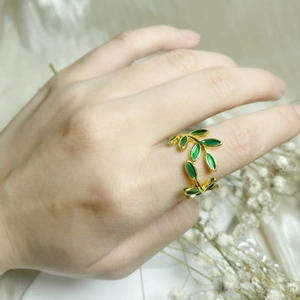 Detailed view of copper ring with green enamel leaves on elegant white silk background