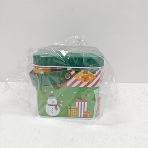 Close-up of Christmas tin gift box with snowman pattern and green leather handle