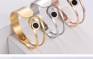 Detailed view of three minimalist titanium steel bangles in gold, silver, and rose gold finishes
